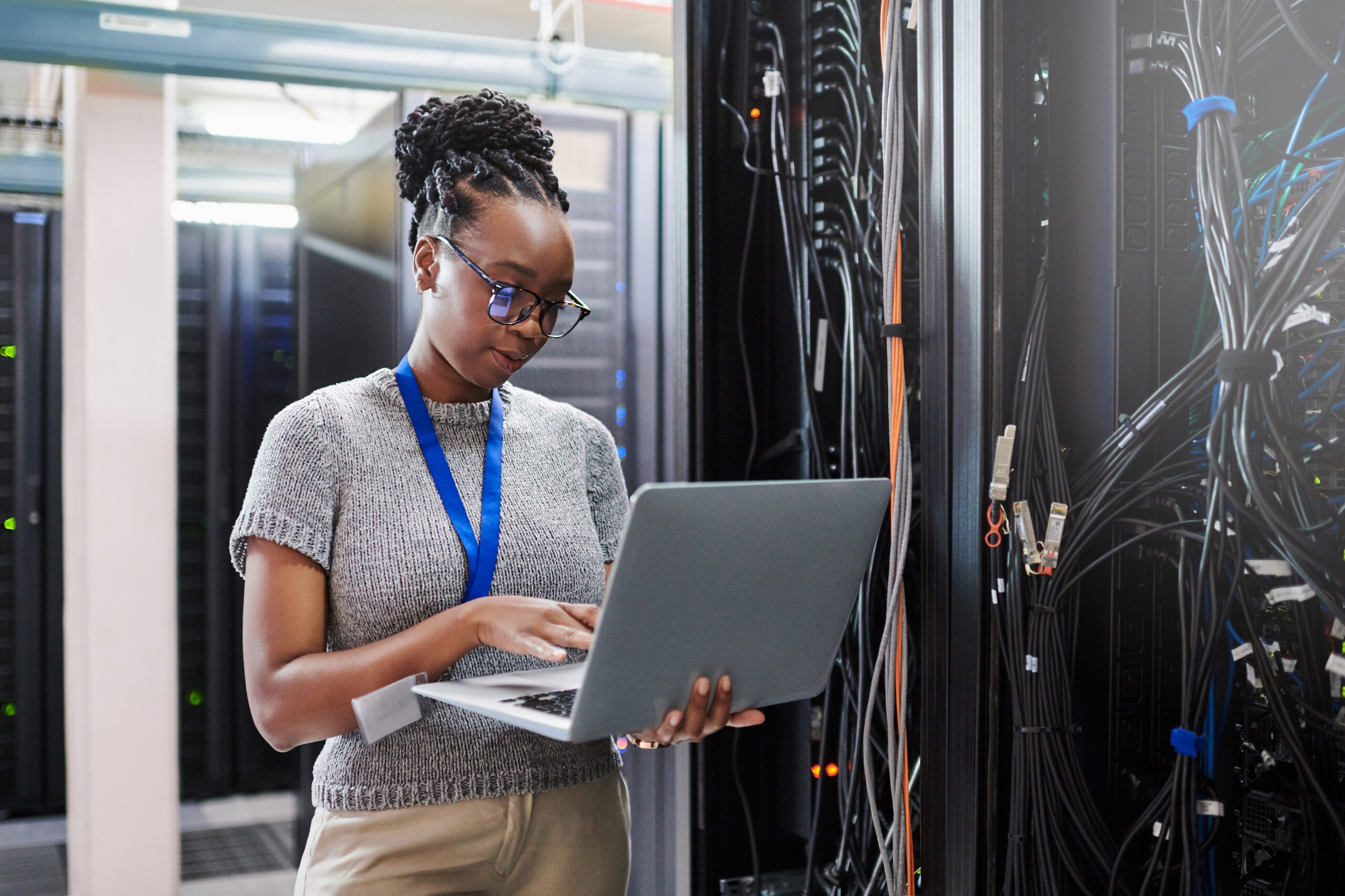 Shot of a young woman using a laptop in a server room
