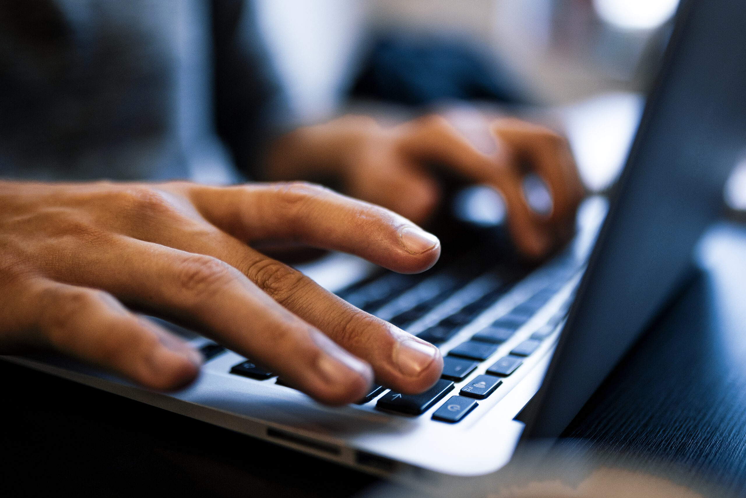 Close up man hands typing on a computer laptop keyboard