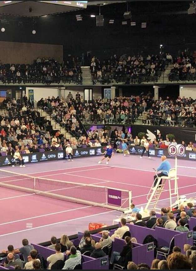 Palais des Sports de Caen la Mer pendant un match sportif, avec public dans les gradins et ambiance dynamique. Salle omnisports moderne accueillant compétition et spectateurs.