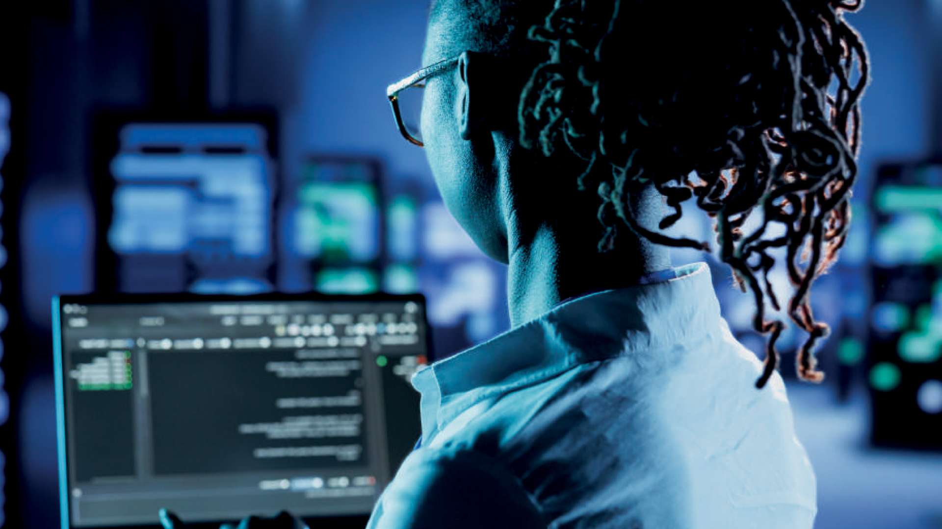 Professionnelle de la sécurité informatique utilisant Heliaq Endpoint Shield sur un ordinateur portable, avec des données de surveillance affichées dans une salle de contrôle. Symbolise la protection des endpoints.