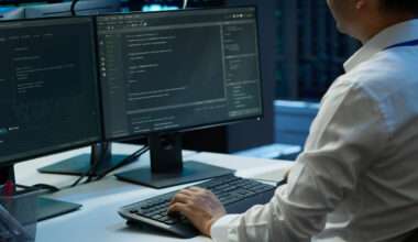 Développeur informatique travaillant sur double écran avec code et environnement de développement dans un data center moderne