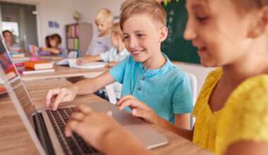 Enfants utilisant un ordinateur portable en classe pour un apprentissage numérique avec outils pédagogiques et environnement scolaire