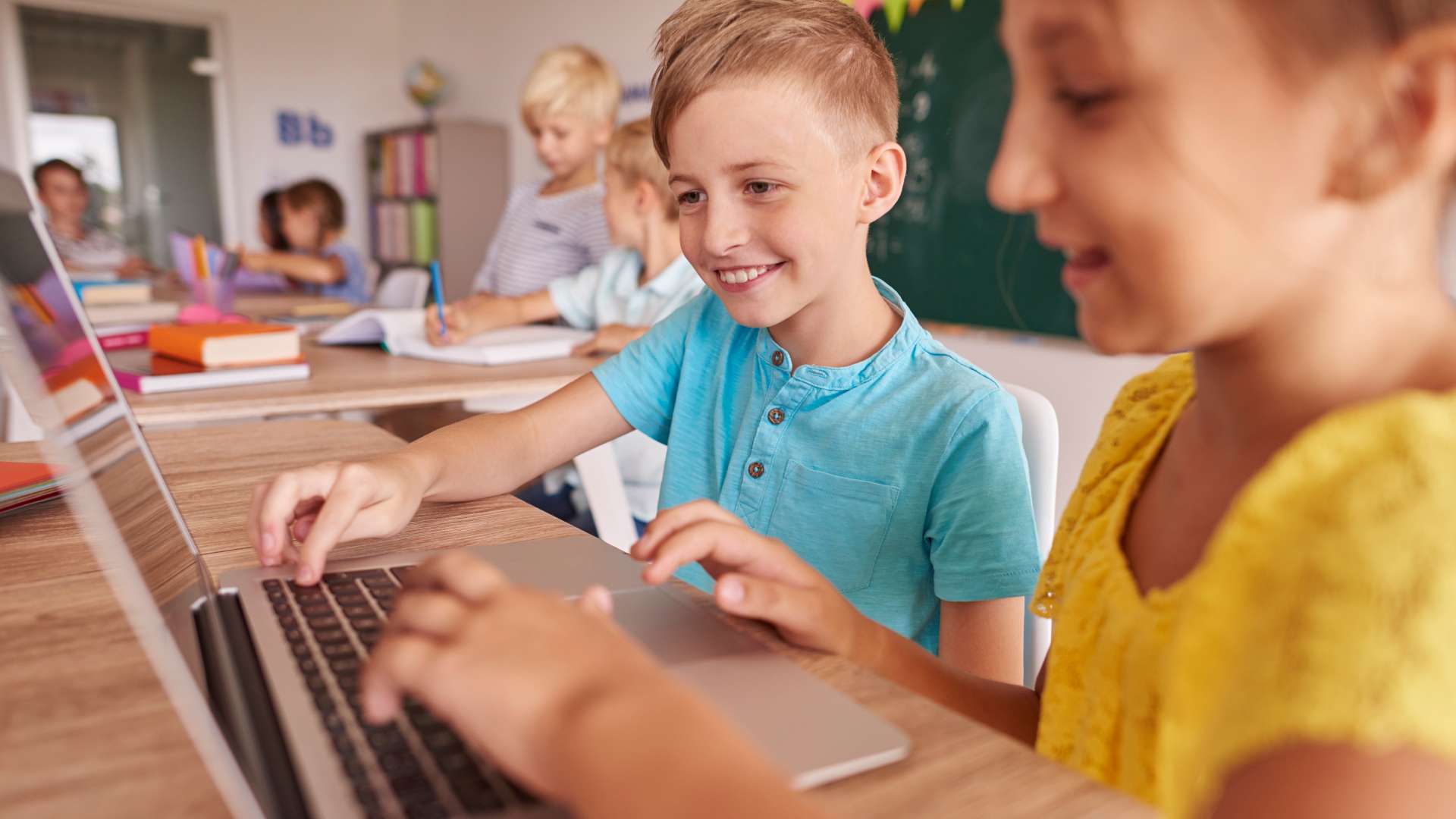 Enfants utilisant un ordinateur portable en classe pour un apprentissage numérique avec outils pédagogiques et environnement scolaire