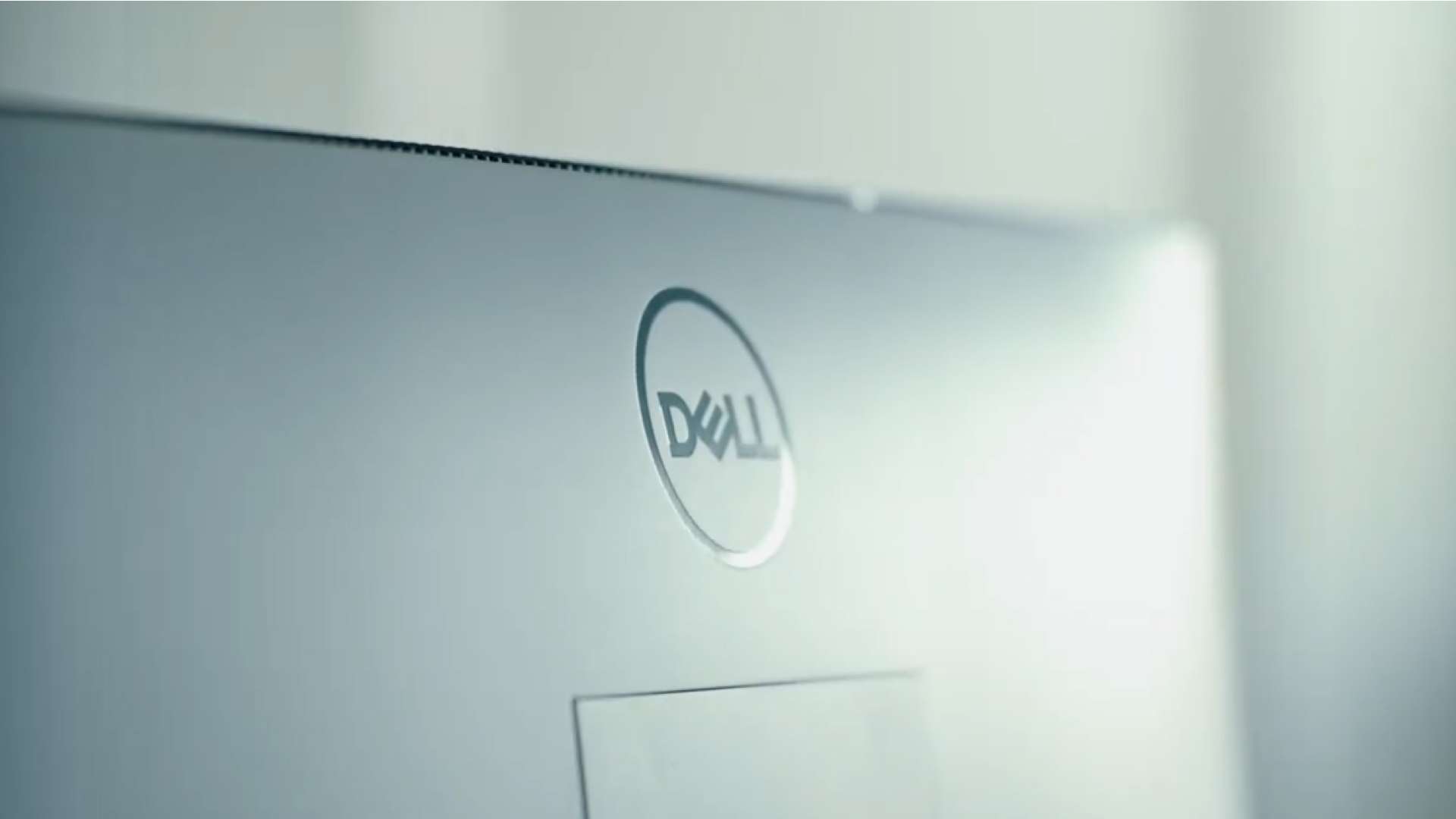 Gros plan sur l’arrière d’un ordinateur portable ou d’un écran de marque Dell, avec le logo circulaire visible sur une surface claire et légèrement floutée.