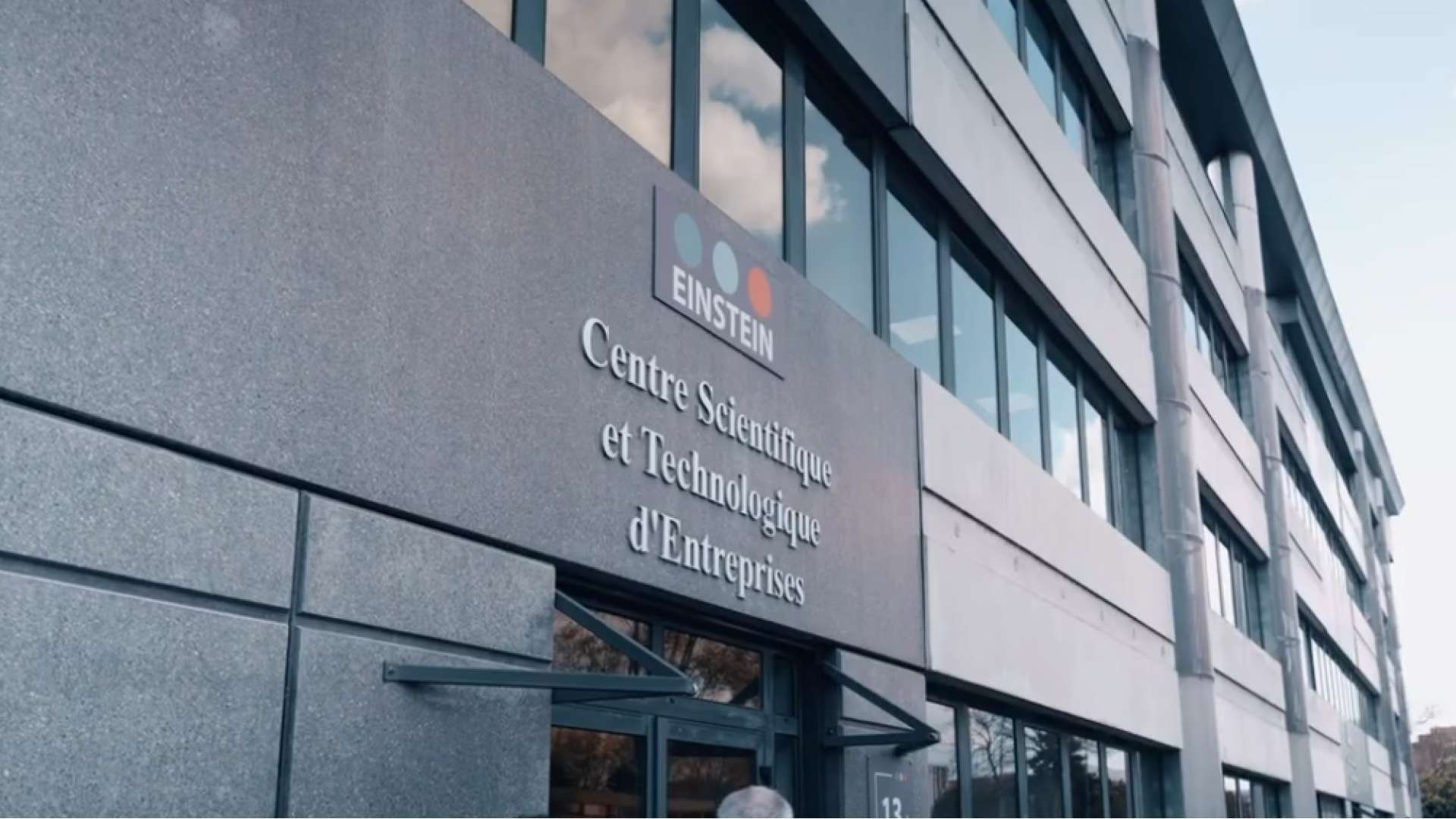 Façade moderne d’un bâtiment avec une enseigne indiquant «?EINSTEIN – Centre Scientifique et Technologique d’Entreprises?», au-dessus d’une entrée vitrée, avec rangée de fenêtres et colonnes sur le côté.